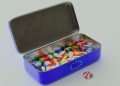A tin containing badges with the flags of EU member states, with a badge of the UK flag sat outside the tin.